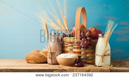 Milk, Chocolate Milk Bottles And Basket With Fruits On Wooden Table. Jewish Holiday Shavuot Concept.