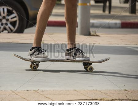 A Skater On His Skateboard On A Sidewalk, Photographed From The Knees Down.