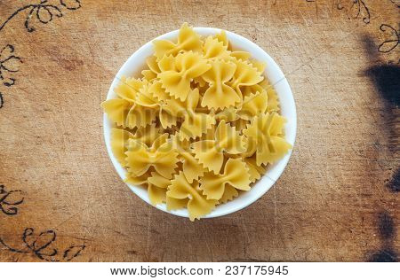 Farfalle Raw Farfallini Pasta In A White Cup On A Wooden Cutting Board, Textured Background, In The 