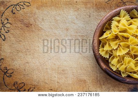 Farfalle Raw Farfallini Pasta In A Wooden Bowl On A Cutting Wooden Board, Texture Background With A 