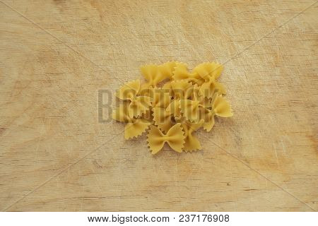 Farfalle Raw Farfallini Background With Pasta On Wooden Board Background. A View From The Top, A Clo