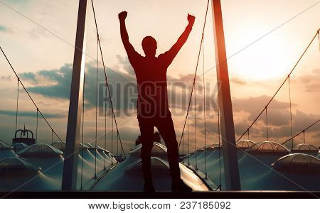 Winner Concept: Silhouette Champion Hand Holding Gold Medal Reward Against Blurred Sport Stadium Sun