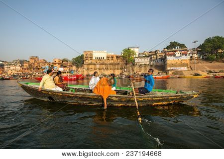 VARANASI, INDIA - MAR 26, 2018: Boatmen on a boat glides through water on Ganges river along shore of Varanasi. According to legends, the city was founded by God Shiva about 5000 years ago.