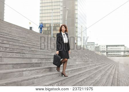 European Businesswoman Going Down On Stairs In High Buildings Background. Concept Of Career And Busi