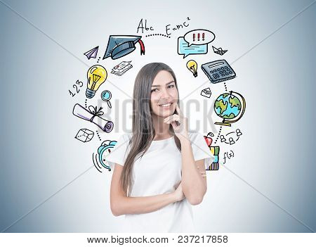 Smiling Young Woman With Fair Hair Wearing A White T Shirt And Thinking While Looking At The Viewer.