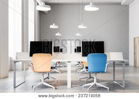 Orange And Blue Chairs Open Office Interior With A Conrete Floor, Rows Of Computer Desks And Blue An