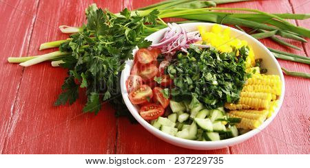 White Plate With Cut Vegetables For A Vegan Salad On The Red Wooden Table. Colorful Photo. Corn, Che
