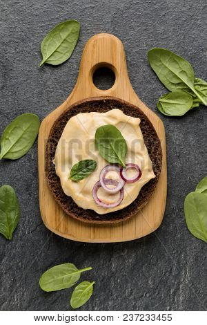 Open faced hummus sandwich canape or crostini on a wooden serving board  on dark stone background closeup. Top view.