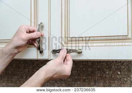 Installation Of Kitchen Furniture. A Man Is Putting Handles To Door Cabinets.