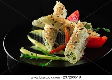 Puff Pastry With Spinach And Cheese Filling On A Black Plate And Black Background.