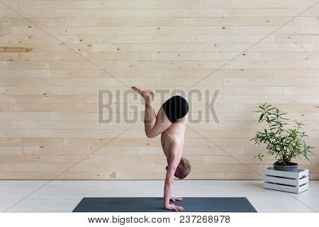 Sporty Man Practices Yoga Handstand Asana Adho Mukha Vrikshasana At The Yoga Studio. Balance Exercis