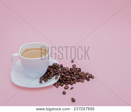 Grains Of Roasted Coffee Scattered From A Cup On A Pink Background, Copy Space.