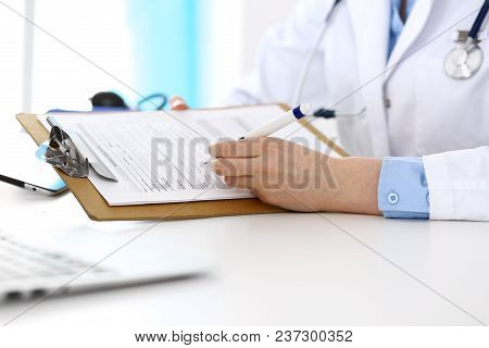 Female Doctor Filling Up Medical Form On Clipboard Closeup.  Physician Finishing Up Examining His Pa