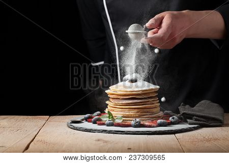 Serving Pancakes With Powdered Sugar And Berries. Chef Man Hand. Beautiful Food Still Life. Slightly