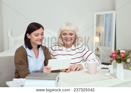 Modern Tablet. Gay Elder Woman And Caregiver Using Tablet While Smiling