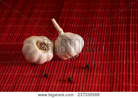 Garlic, Black Pepper On A Red Style Background Table