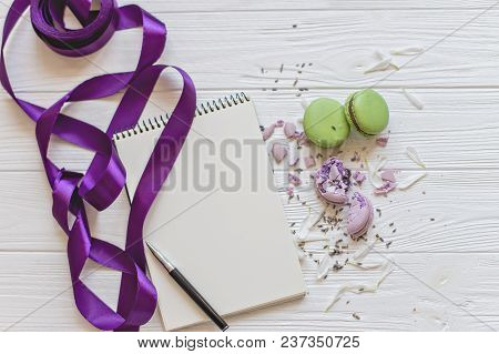 A Flat Lay Of A Macarons , Notebook For Records , The Pen A White Background