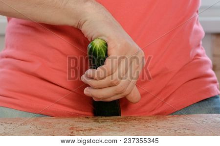 Man Plays With A Cucumber Between His Legs Standing Near The Table. Cucumber Closeup
