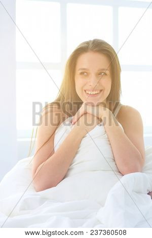 Young caucasian woman covering her head and ears with pillows