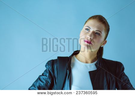 portrait of beautiful young brunette woman in stylish black jacket on gray.