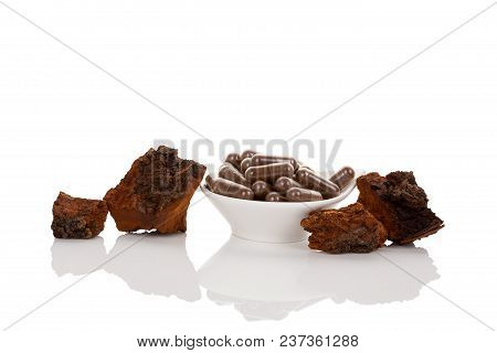 Inonotus Obliquus, Chaga Pieces And Powder In Gel Capsules In Bowl Isolated On White Background. Med