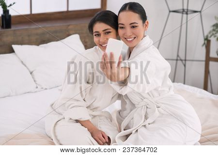 Selfie Time. Positive Joyful Attractive Women Looking Into The Smartphone Camera While Taking A Self