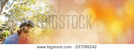 Man in forest with virtual reality headset looking up with orange bokeh transition