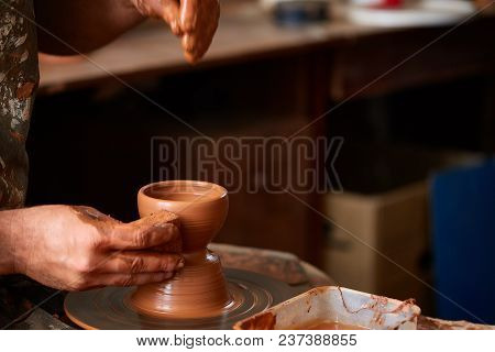 Close-up Hands Of A Male Potter In Plaid Shirt And Dirty Apron Who Molds A Vase From Clay, Selective