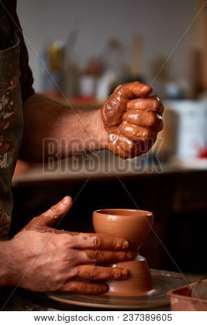 Close-up Hands Of A Male Potter In Plaid Shirt And Dirty Apron Who Molds A Vase From Clay, Selective