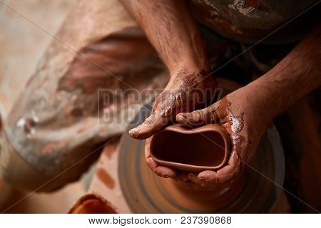 Close-up Hands Of A Male Potter In Plaid Shirt And Dirty Apron Who Molds A Vase From Clay, Selective