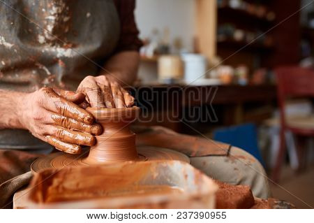 Close-up Hands Of A Male Potter In Plaid Shirt And Dirty Apron Who Molds A Vase From Clay, Selective