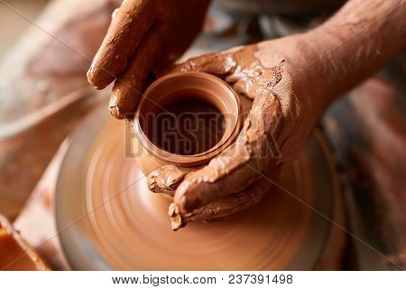 Close-up Hands Of A Male Potter In Plaid Shirt And Dirty Apron Who Molds A Vase From Clay, Selective