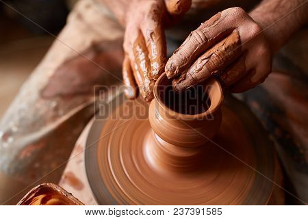Close-up Hands Of A Male Potter In Plaid Shirt And Dirty Apron Who Molds A Vase From Clay, Selective