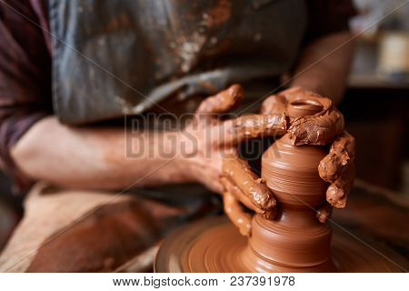 Close-up Hands Of A Male Potter In Plaid Shirt And Dirty Apron Who Molds A Vase From Clay, Selective