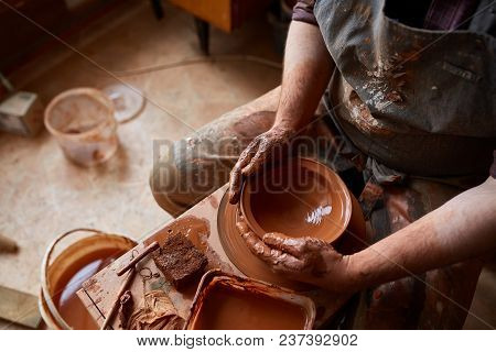 Close-up Hands Of A Male Potter In Plaid Shirt And Dirty Apron Who Molds A Vase From Clay, Selective
