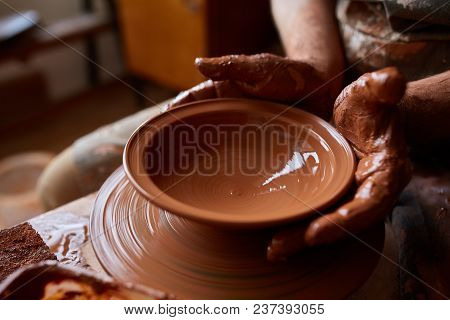 Close-up Hands Of A Male Potter In Plaid Shirt And Dirty Apron Who Molds A Vase From Clay, Selective