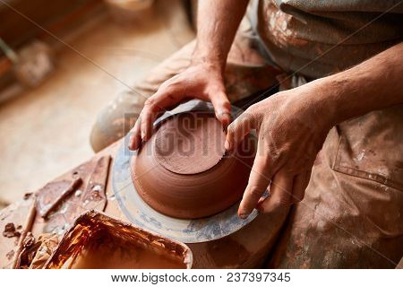 Close-up Hands Of A Male Potter In Plaid Shirt And Dirty Apron Who Molds A Vase From Clay, Selective