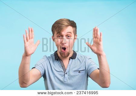Young Hipster Man With Holding Something Very Big, Size Concept Over Blue Background.