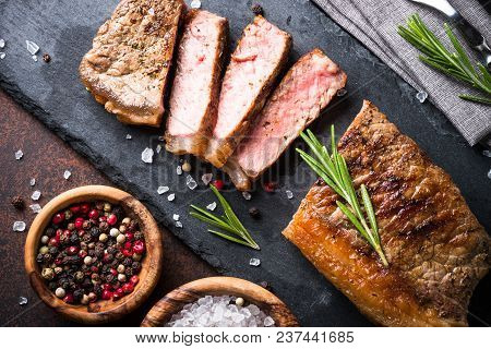Beef Steak. Grilled Striploin Steak On Cutting Board With Nerbs And Spices. Top View.