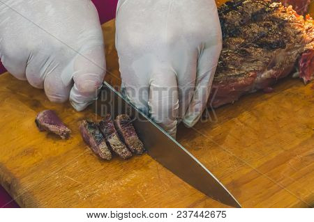 Cook In White Gloves Clean Cut Grilled Marble Beef On Partial Pieces On A Wooden Board With A Knife