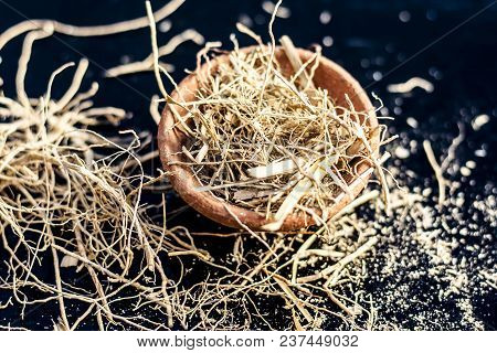 Dried Vetiver Grass Or Khus Or Chrysopogon Zizanioides Grass In A Clay Bowl On Wooden Surface.