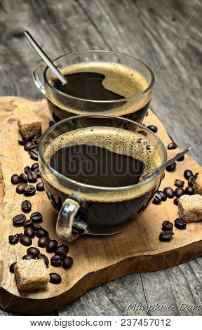 Two Cups Of Coffee,coffee Beans And Brown Lump Sugar On Wooden Background.