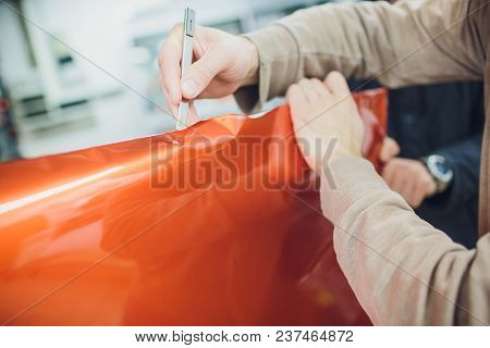 Car Wrapping Specialist Putting Vinyl Foil Or Film On Car. Selective Focus.