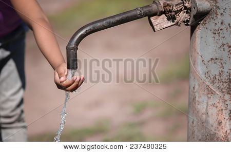 African American child drinking water from tap outdoors. Water scarcity concept