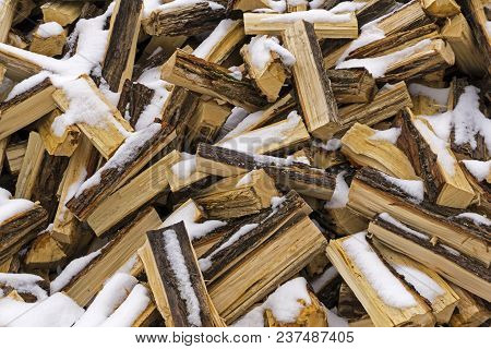 Background - A Messy Heap Of Chopped Logs Lightly Covered With Fallen And Melting Snow