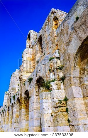 Odeon Of Herodes Attiacus Yellow Flowers Acropolis Athens Greece. Stone Theater Base Of Acropolis.  