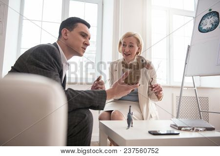 Visualization Of Situation. Concentrated Handsome Man Using Toys While Mature Woman Looking At Him