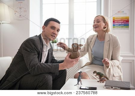 Stress Relief. Attractive Positive Man Looking At Camera While Talking With Mature Psychologist