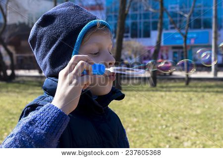 The Boy Blows Bubbles. With A Slight Breeze Of Air They Fly Away.