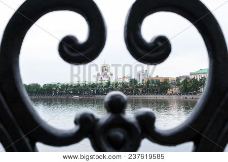 Close-up Beautiful Black Cast Ornate Lattice Fence Of Yekaterinburg Embankment With View Of The Temp